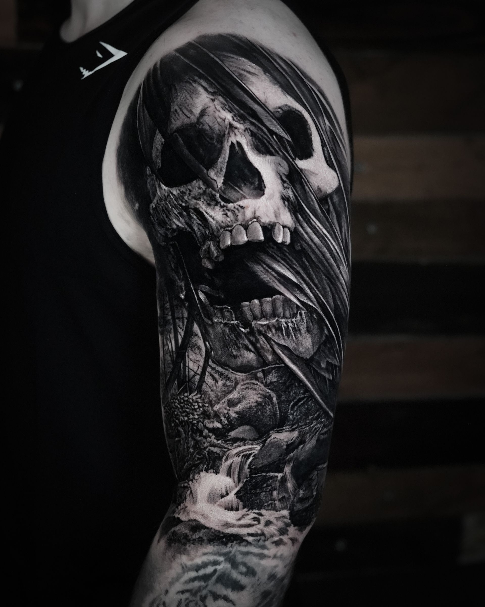 A black and white tattoo of a skull on a man 's arm.