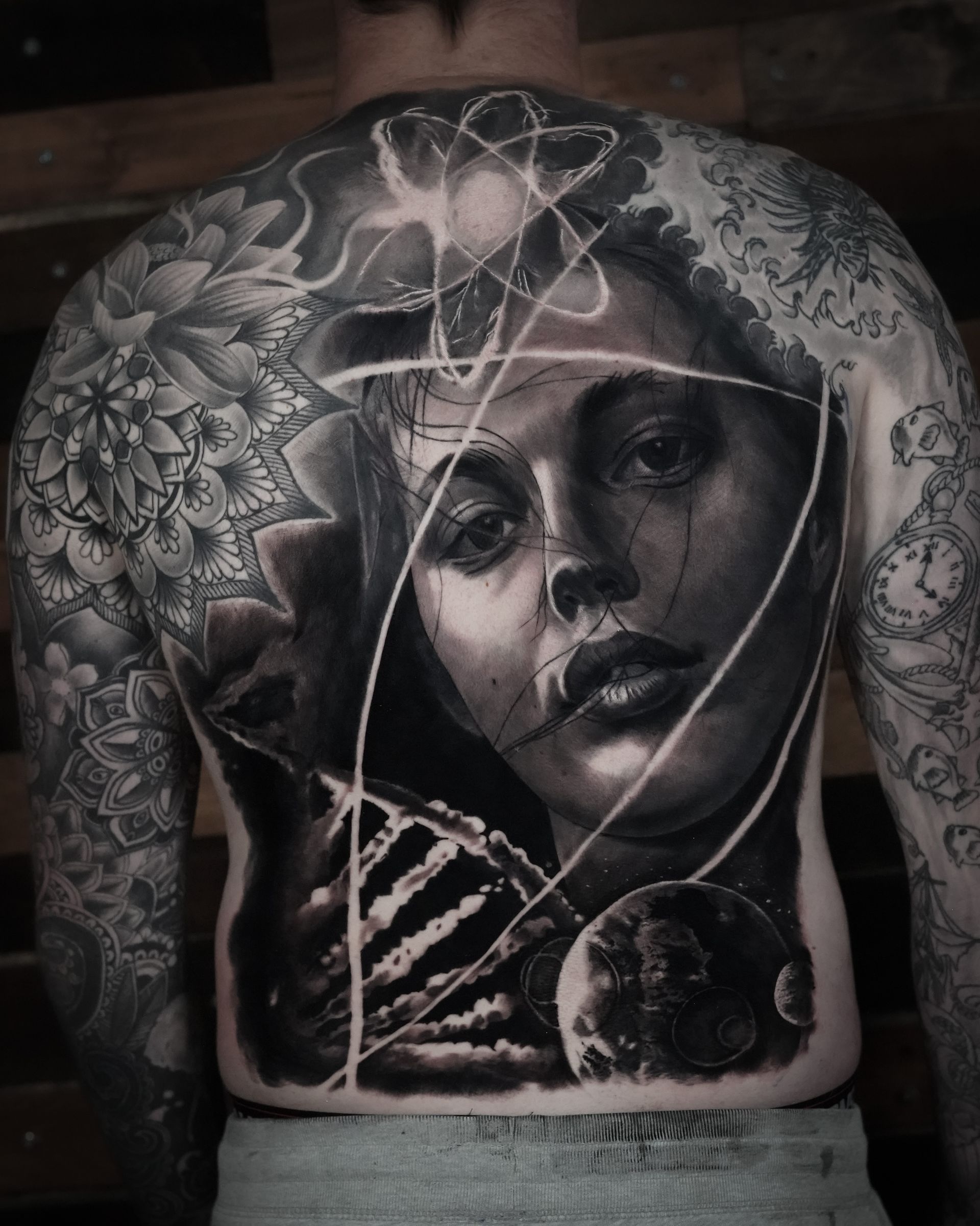 A man has a tattoo on his back of a woman holding a skeleton.