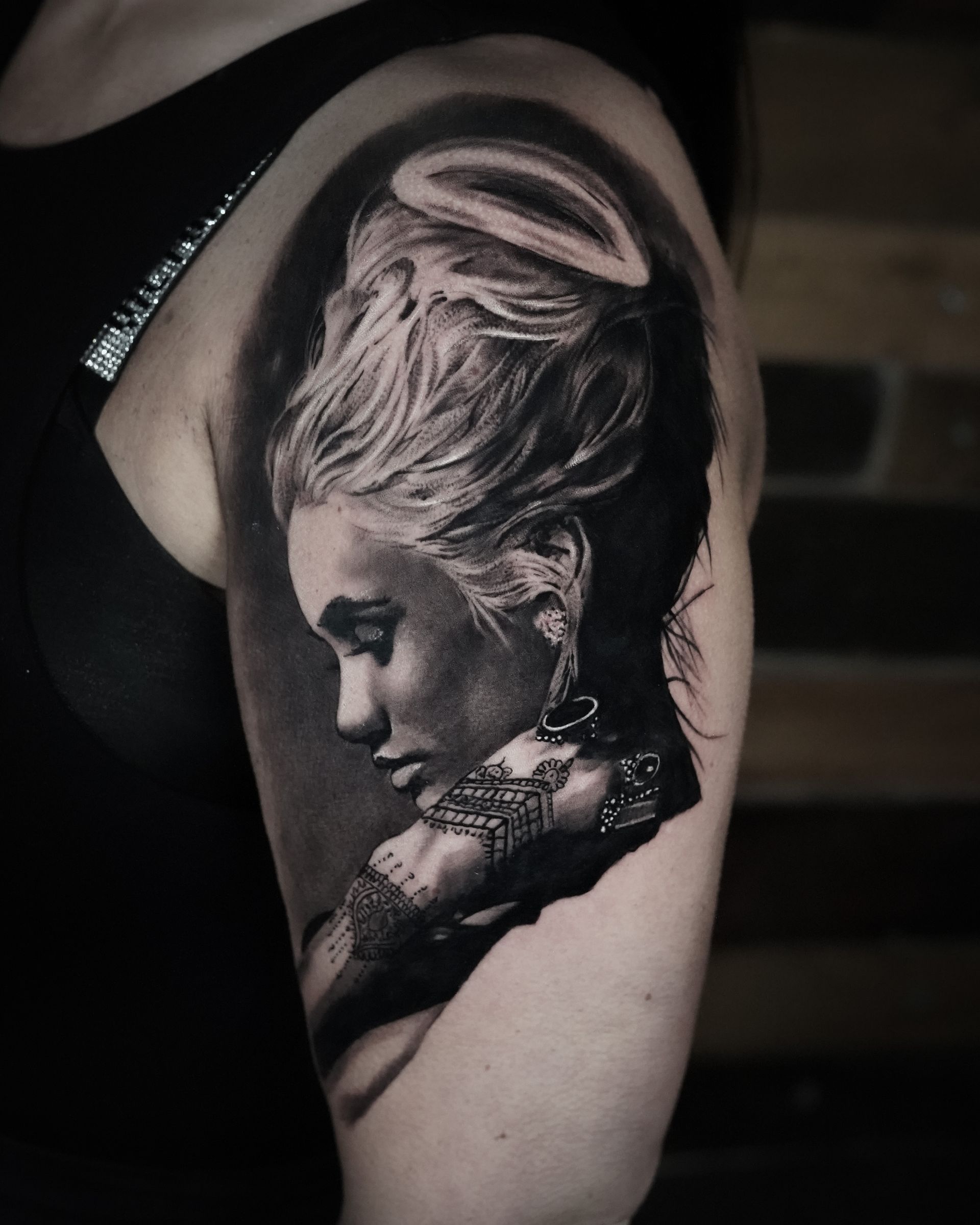 A woman has a tattoo of a woman 's face on her arm.
