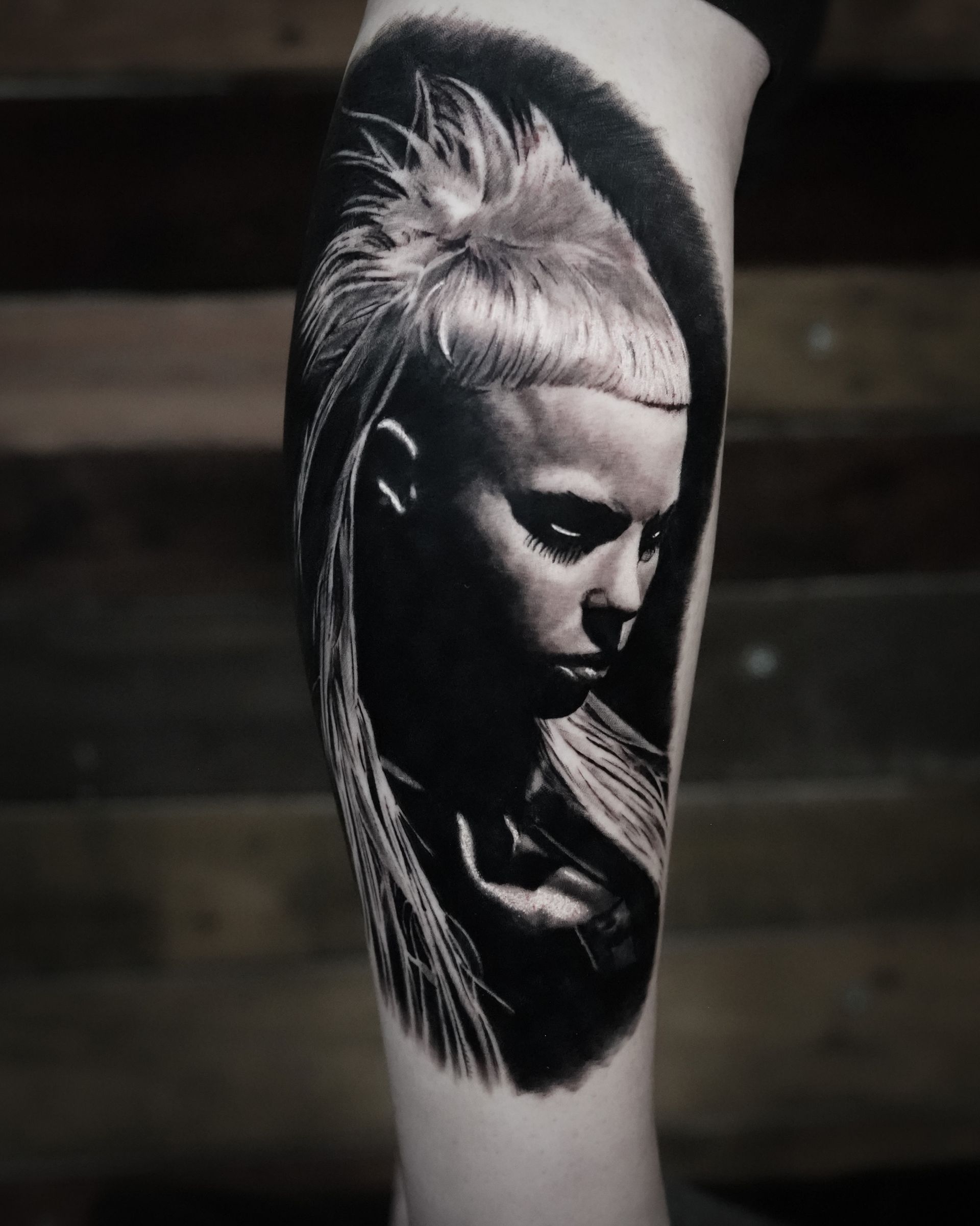 A black and white tattoo of a woman 's face on a leg.