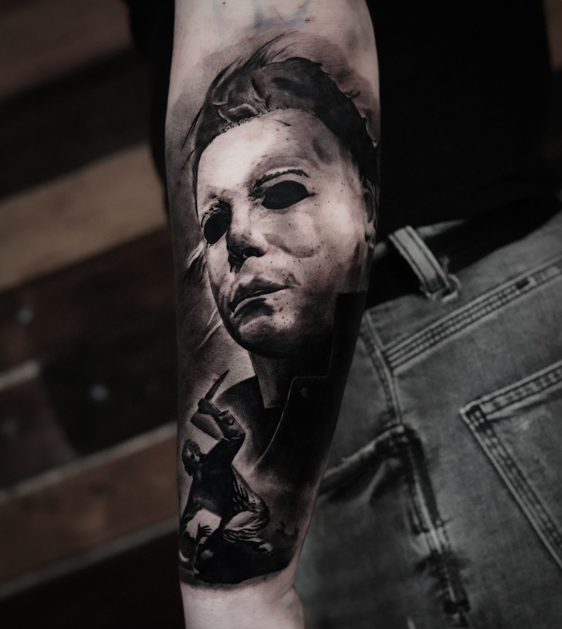A black and white tattoo of michael myers on a man 's arm.