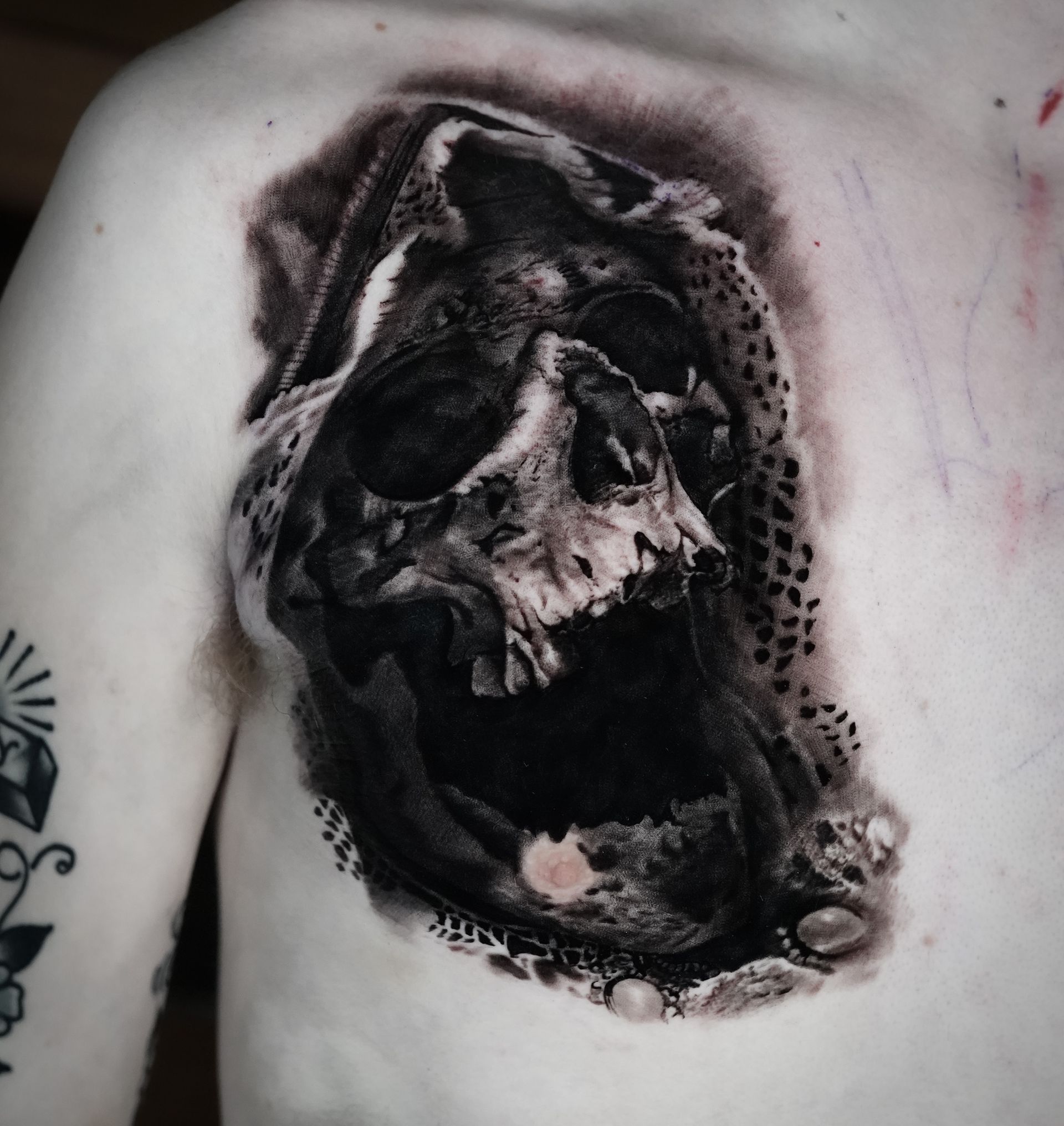 A man has a tattoo of a skull on his chest