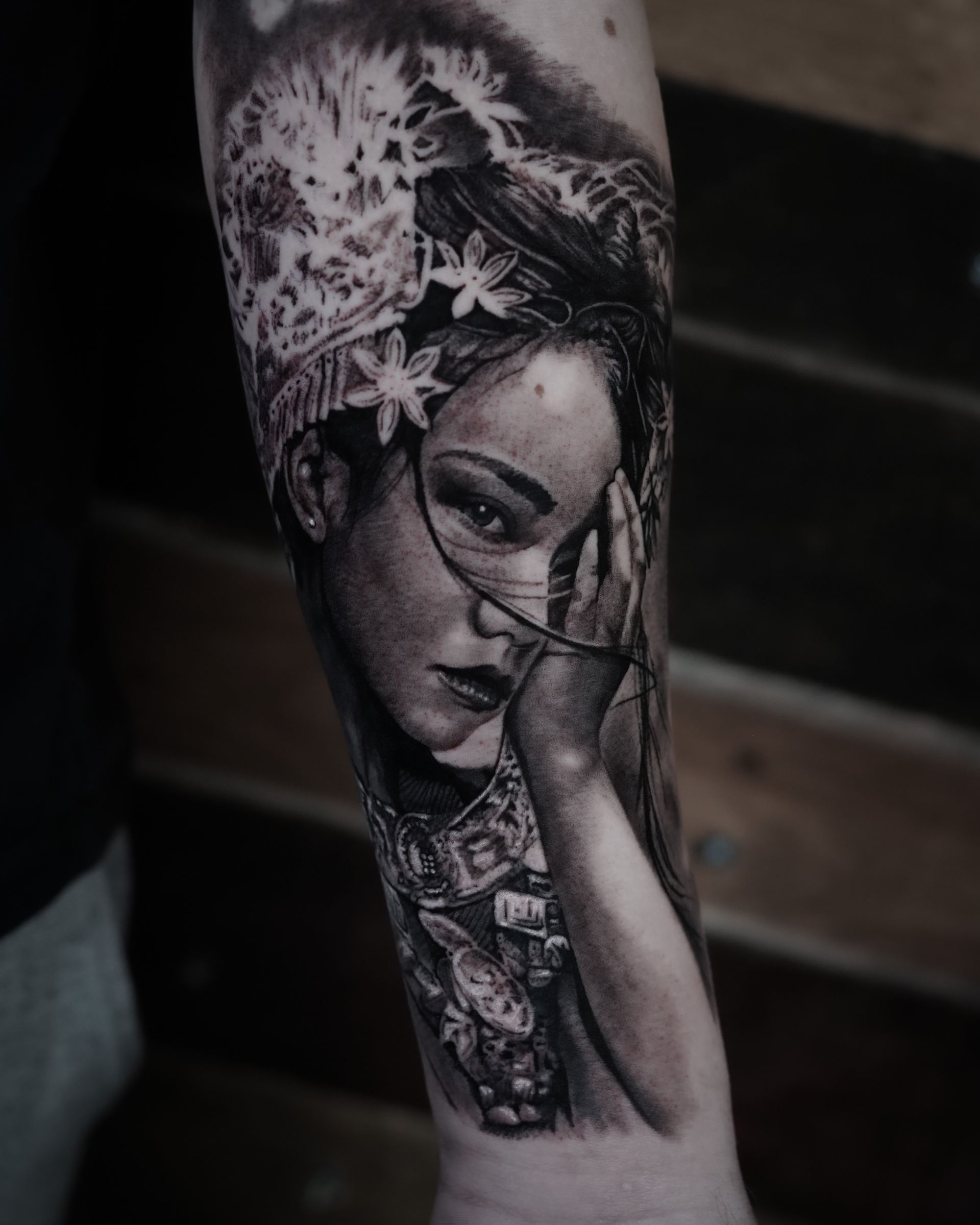 A black and white tattoo of a woman covering her face with her hand.