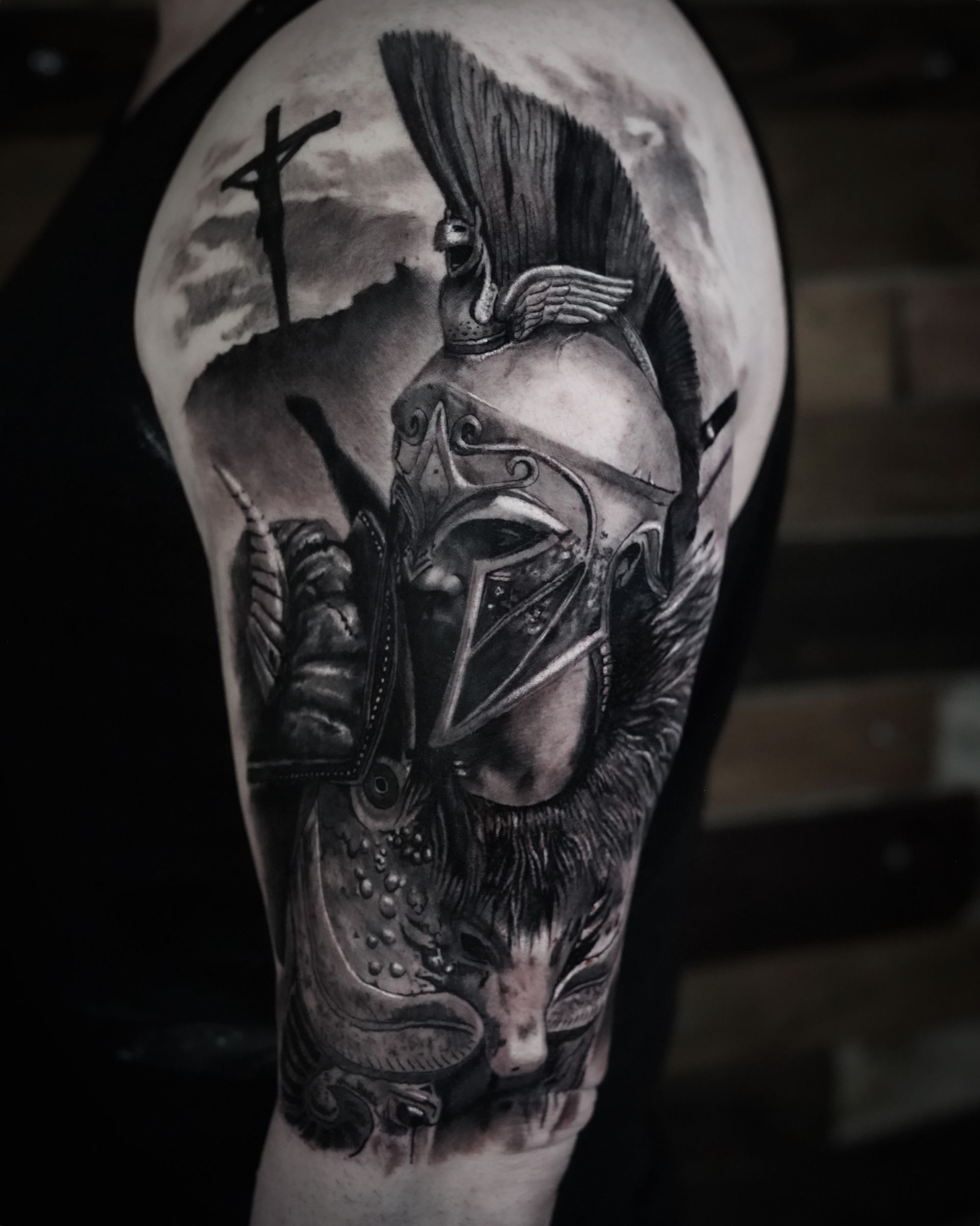 A black and white tattoo of a spartan warrior on a man 's arm.