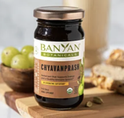 Banyan Botanicals Chyawanprash jar with green apples and herbs on a wooden table
