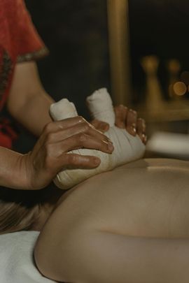 Hands massage wrapped ankles on a person’s leg in a spa setting.