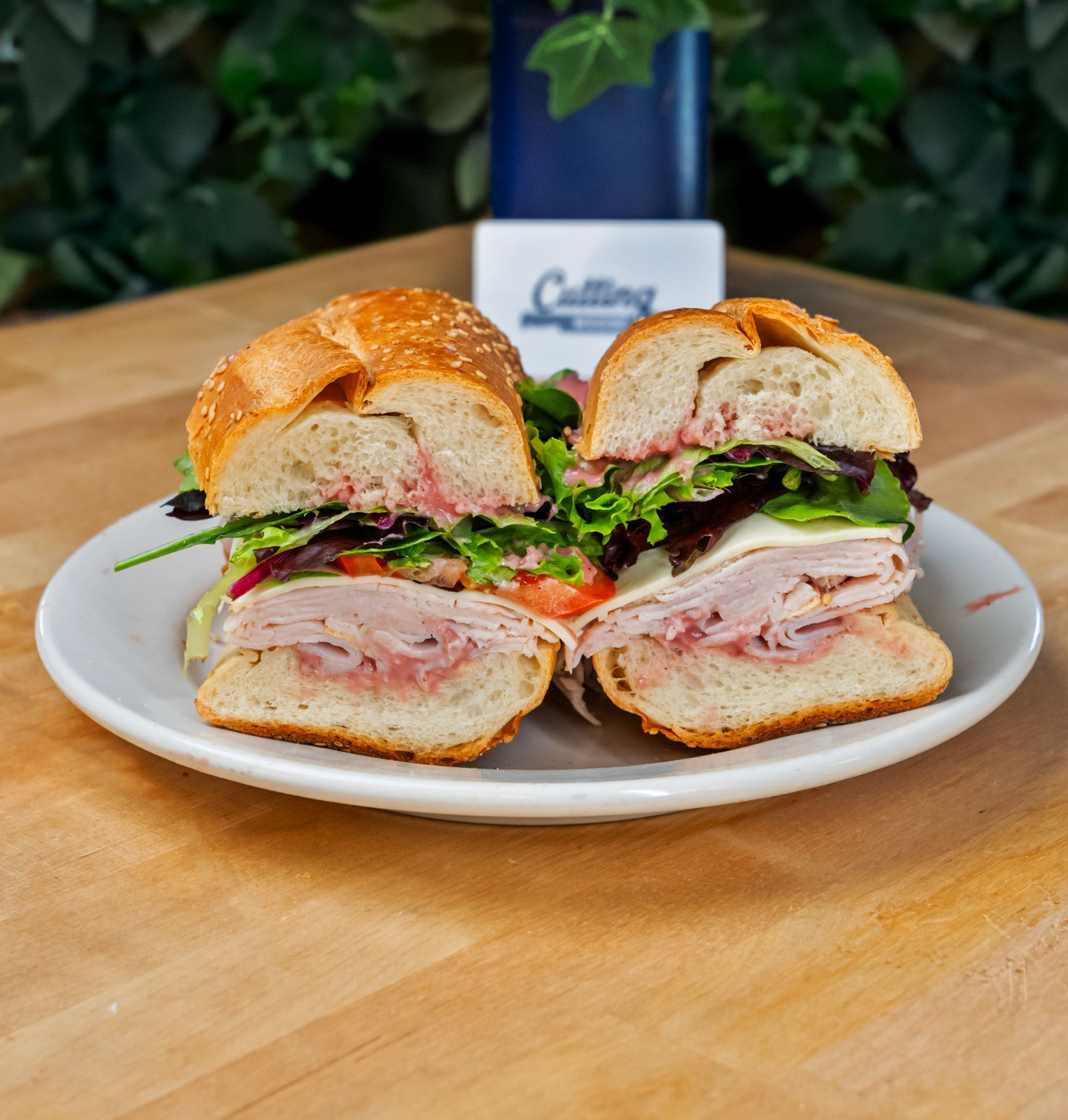 A sandwich on a white plate on a wooden table.