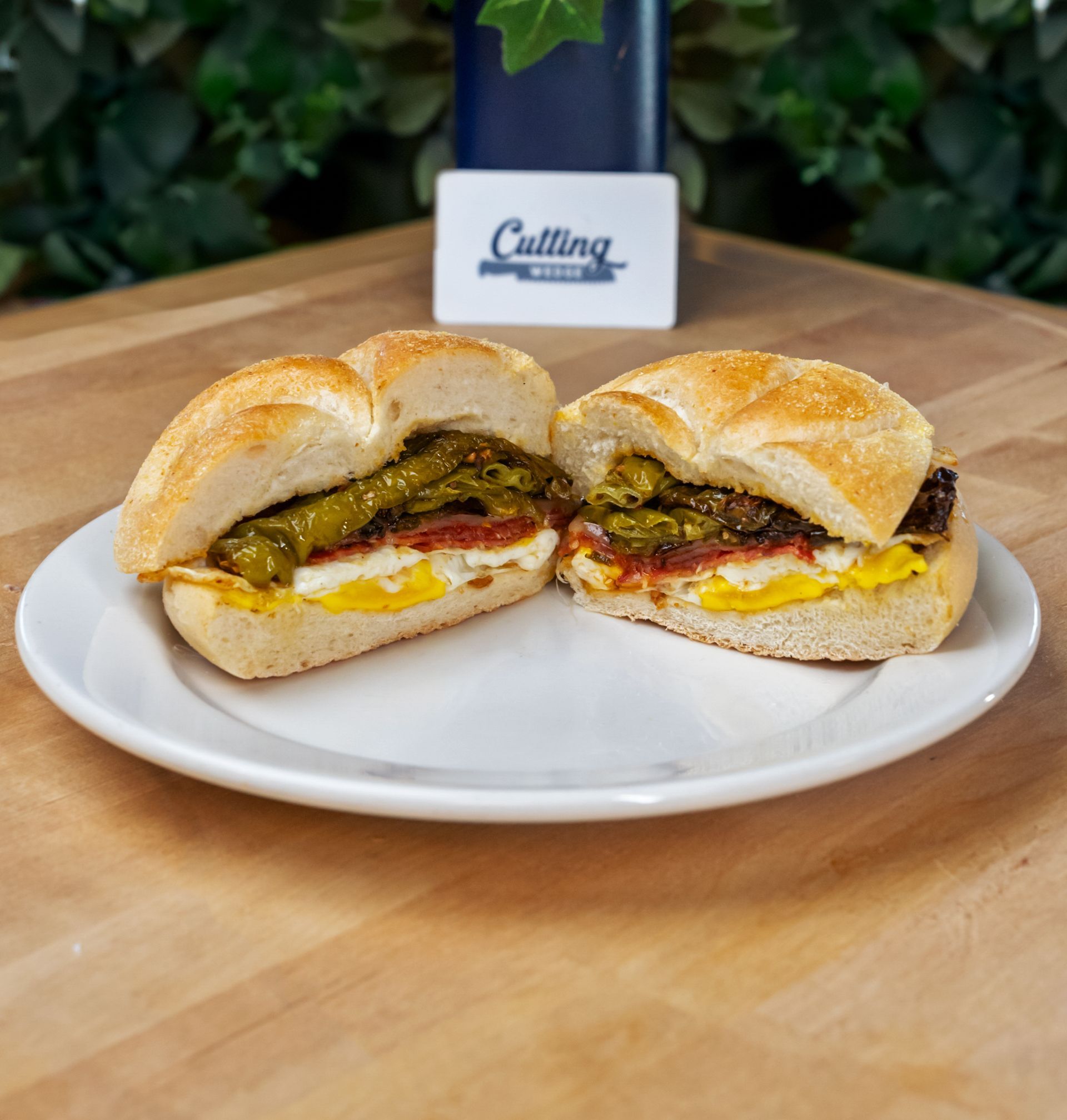 A sandwich is cut in half on a white plate on a wooden table.