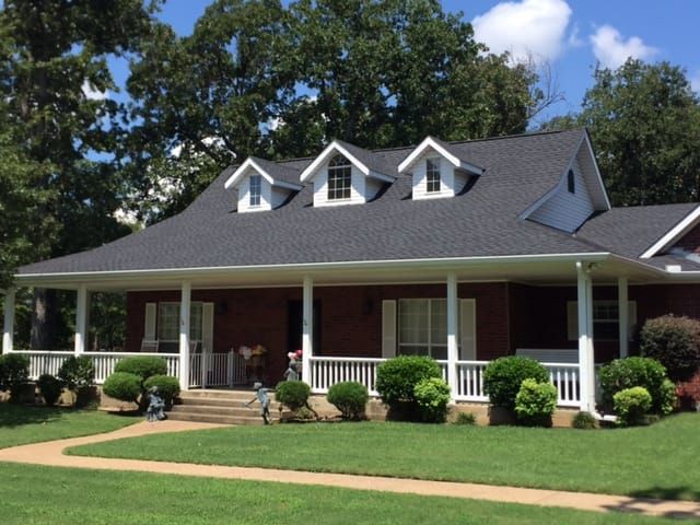 A brick house with a porch and a gray roof
