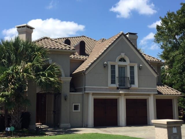 A large house with three garage doors and a balcony