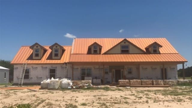 A large house with an orange roof is being built