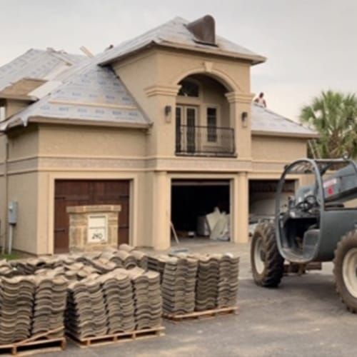 A tractor is parked in front of a large house
