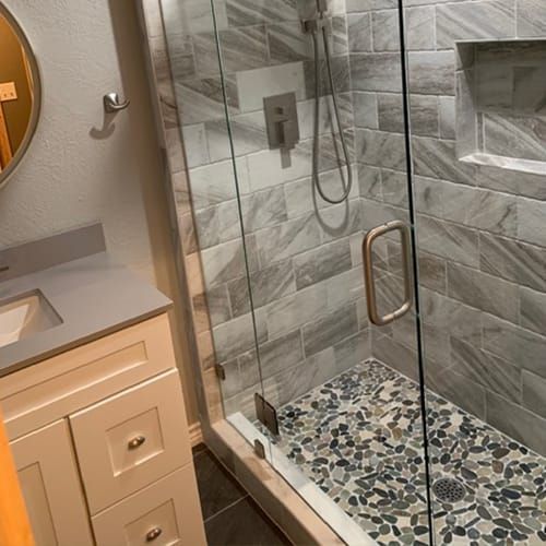 A bathroom with a walk in shower , sink and mirror.