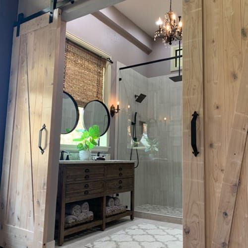 A bathroom with a sliding barn door leading to a shower.