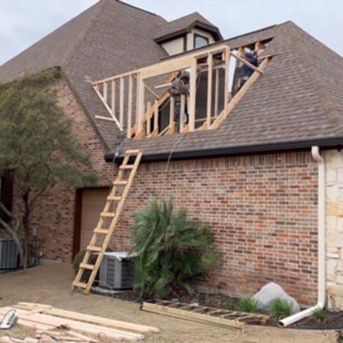 A brick house with a wooden frame being built on top of it.