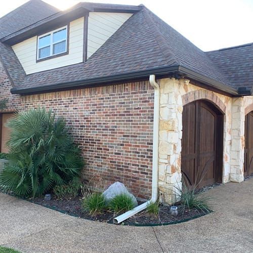 A brick house with two garage doors and a gutter