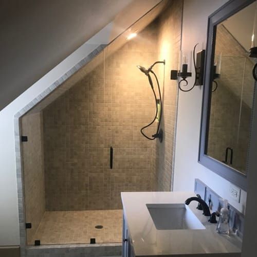A bathroom with a sink and a shower under a sloped ceiling.