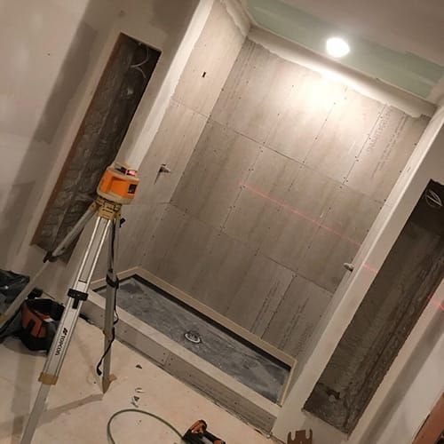 A bathroom under construction with a tripod and a laser level.