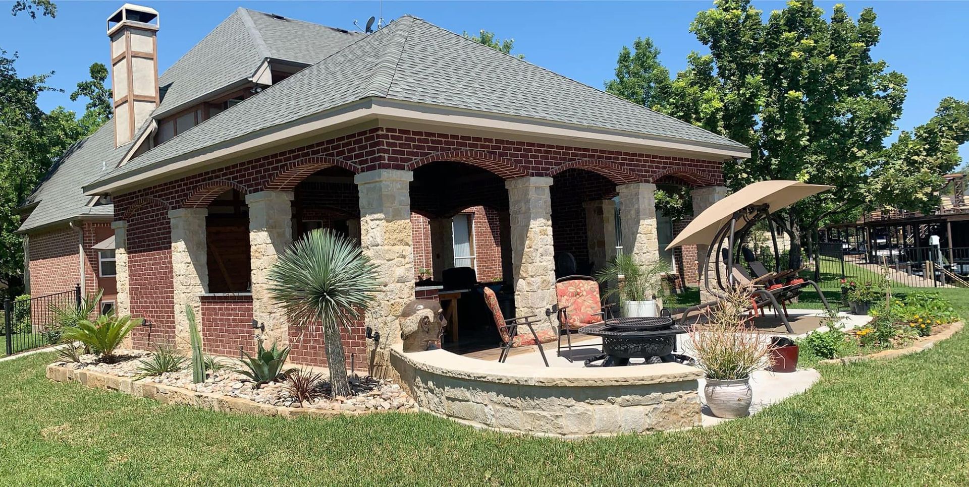 A large brick house with a patio and umbrellas in front of it.