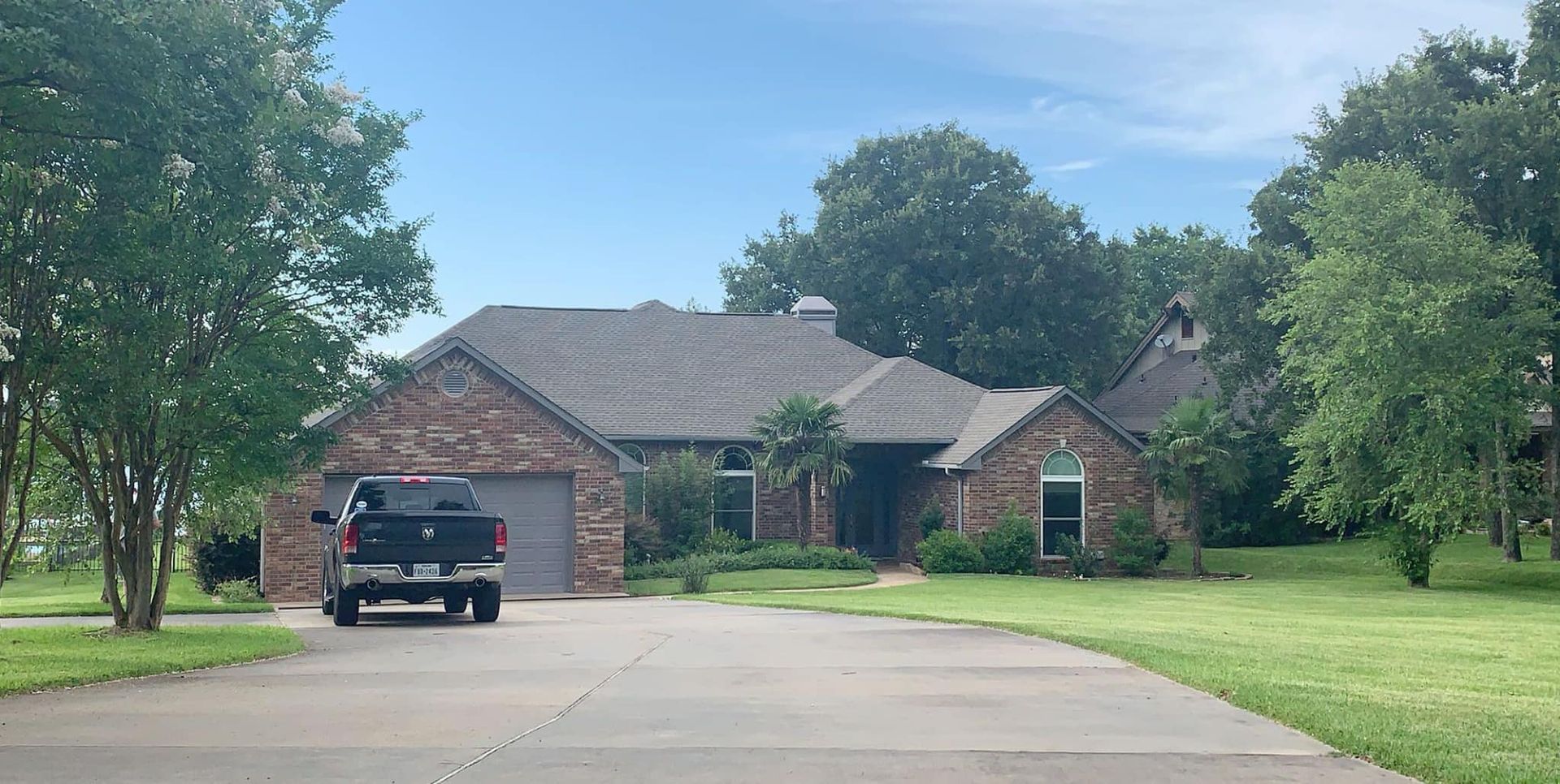 A black truck is parked in front of a brick house.