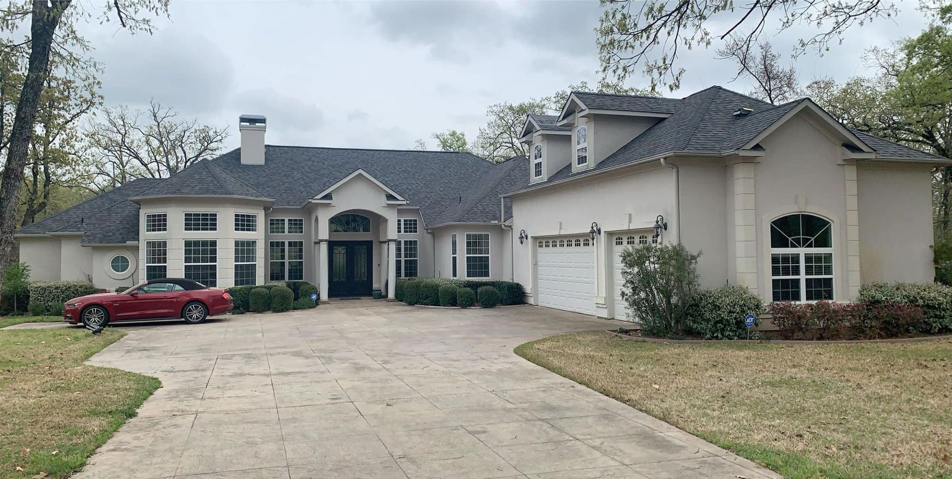 A large white house with a red car parked in front of it
