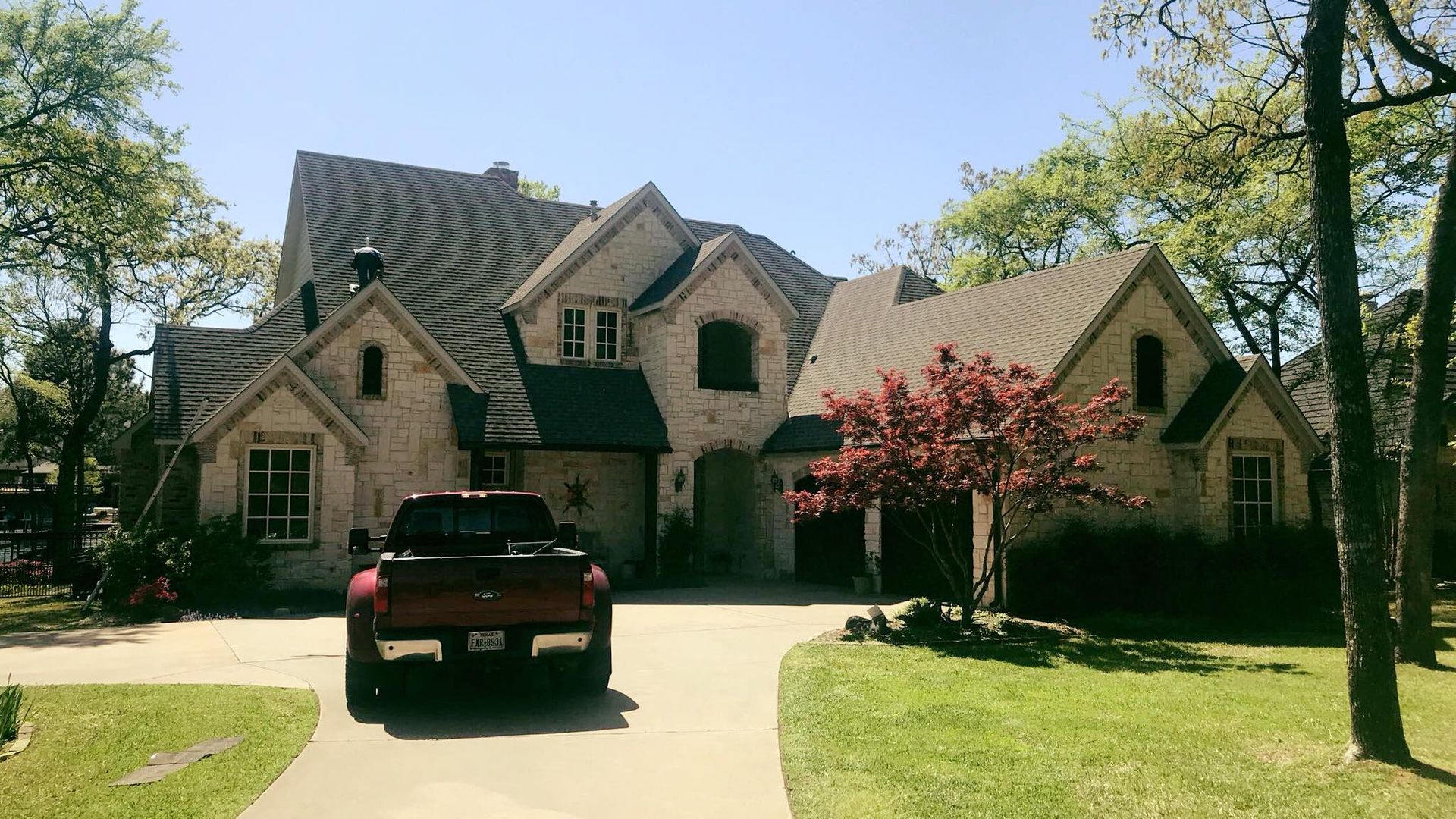 A red truck is parked in front of a large house.