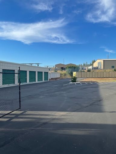 A parking lot with a chain link fence and a building with green doors.