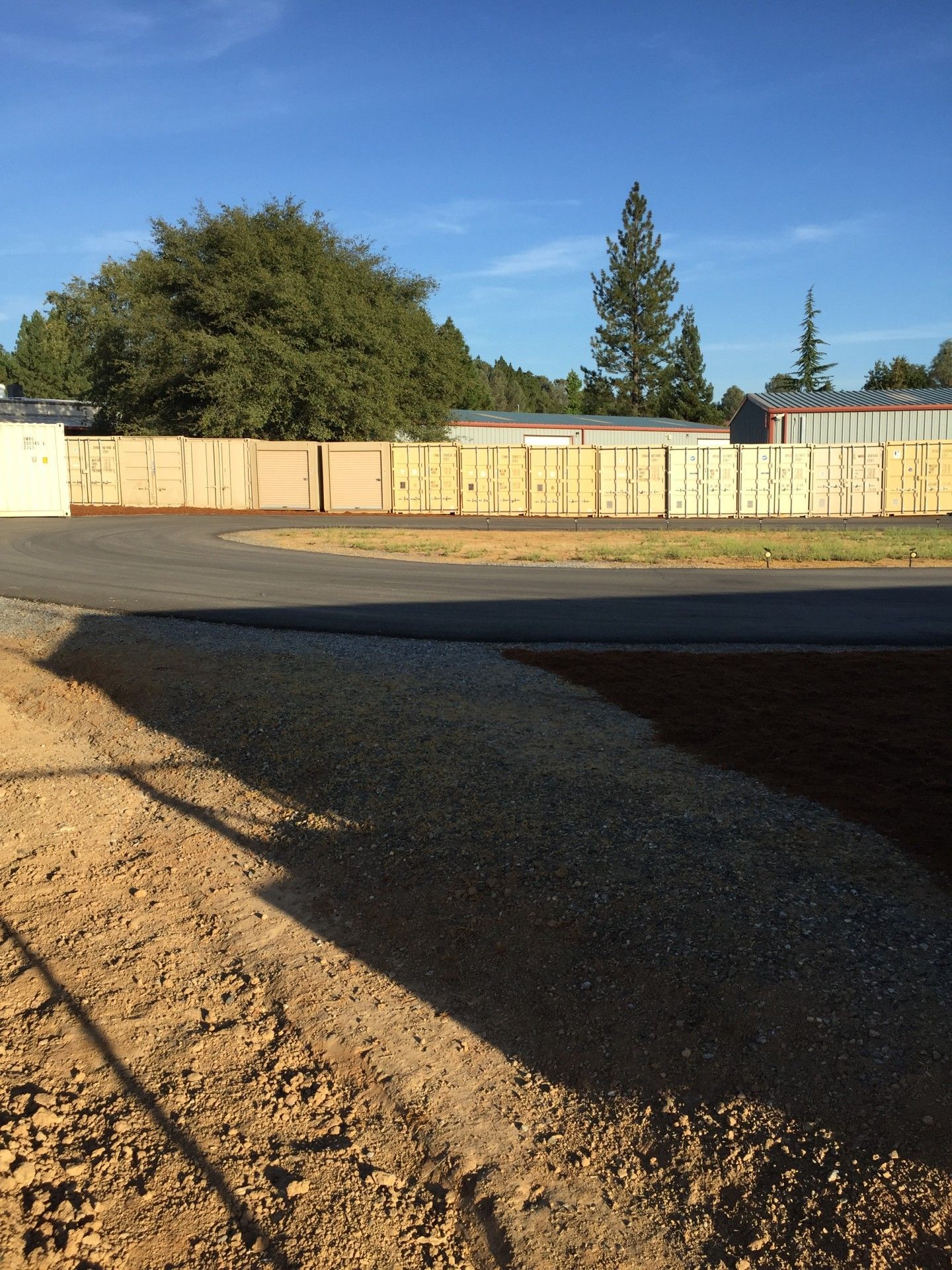 A dirt road with a fence and trees in the background