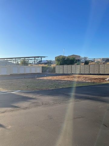 A parking lot with a fence and a blue sky in the background.