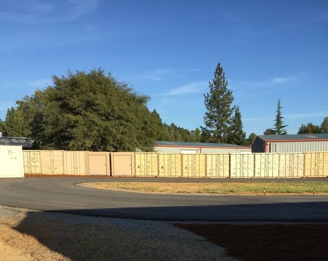 A wooden fence surrounds a parking lot in front of a house.