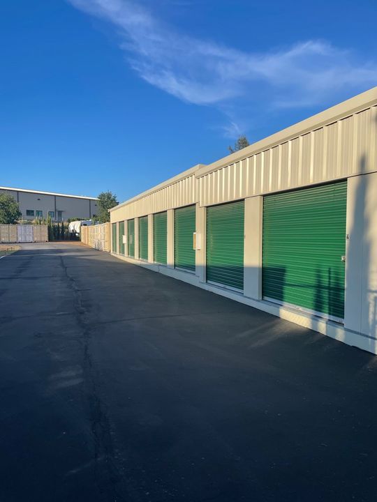 A row of storage units with green doors on a sunny day.