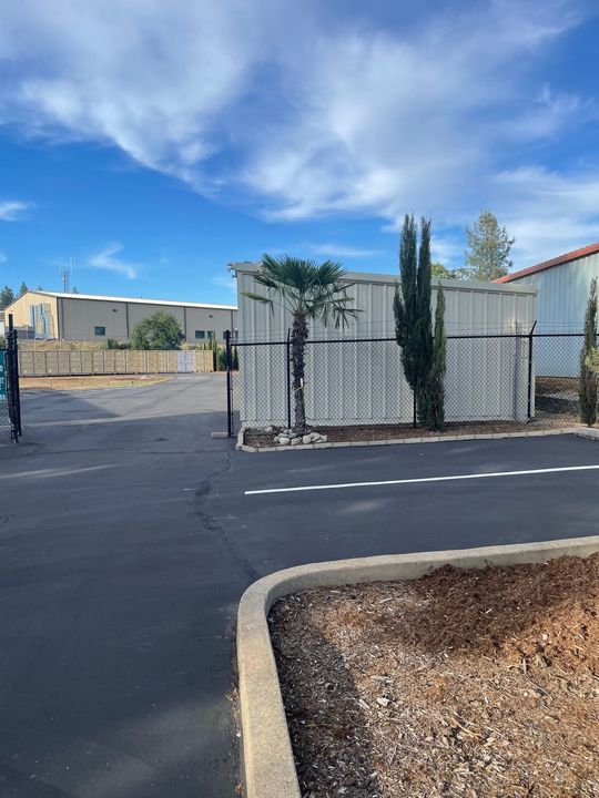 A parking lot with a fence and a palm tree in front of a building.