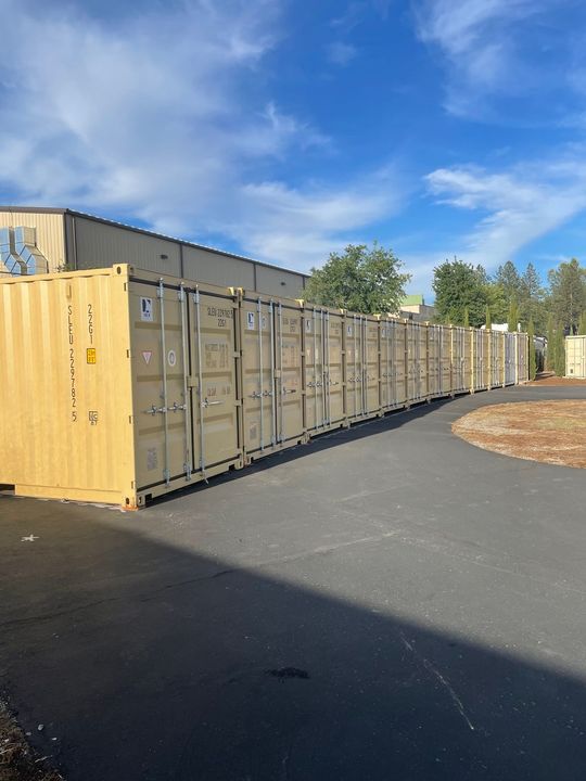 A row of shipping containers are lined up in a parking lot.