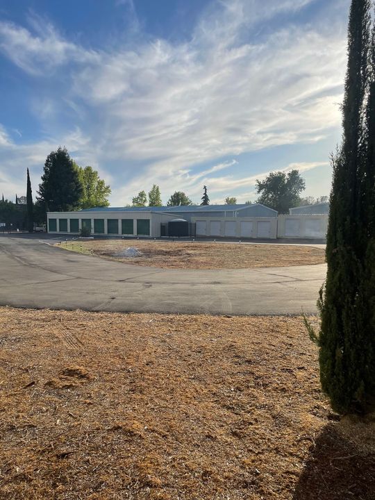 A large white building is sitting in the middle of a dirt field.