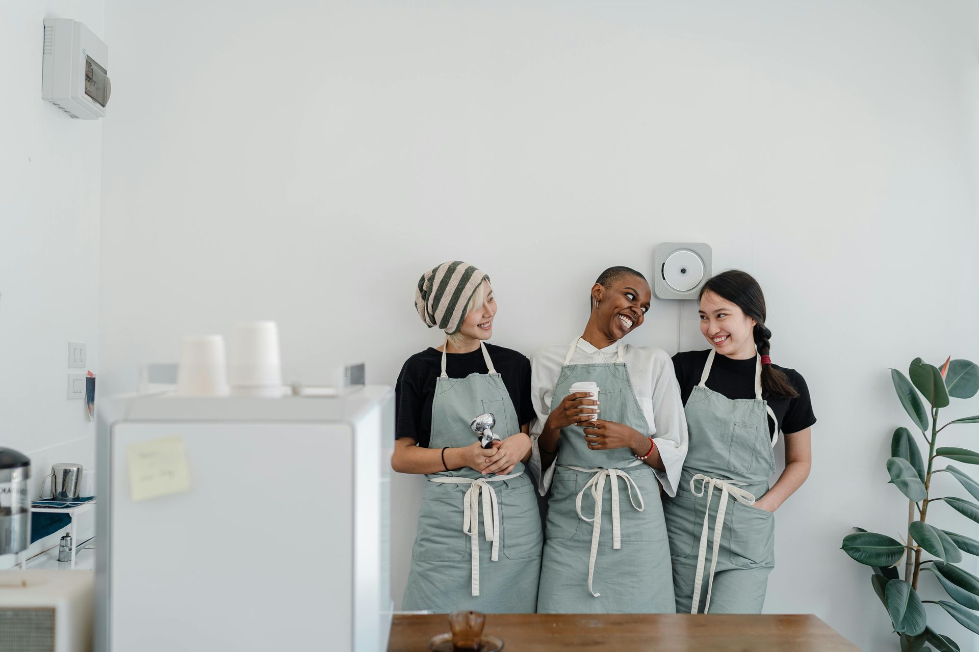 Three women in aprons are standing next to each other in a kitchen.