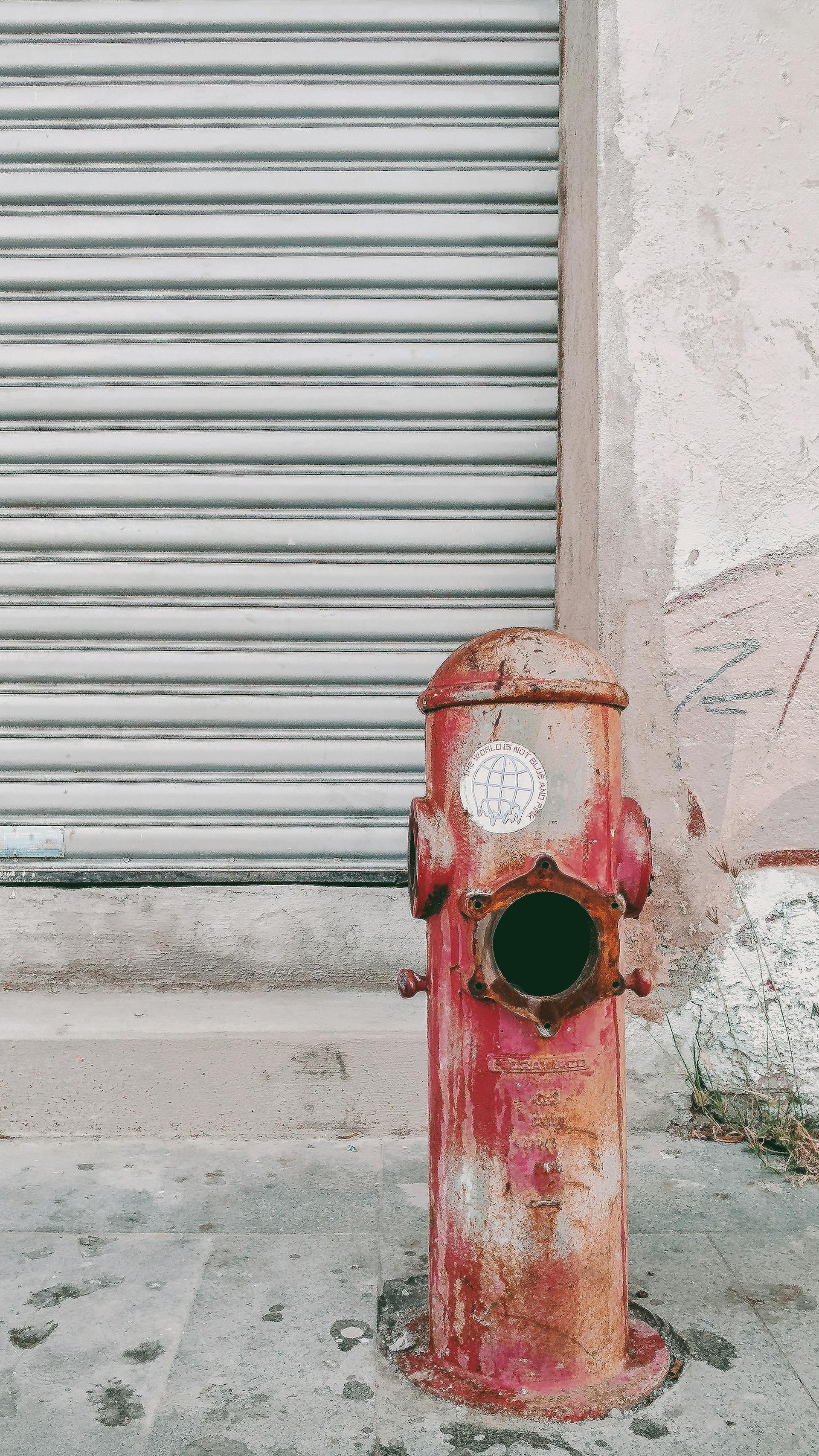 A red fire hydrant is sitting on the side of the road in front of a building.