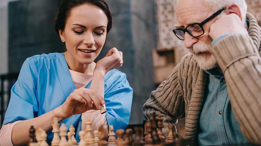nurse playing chess with older man