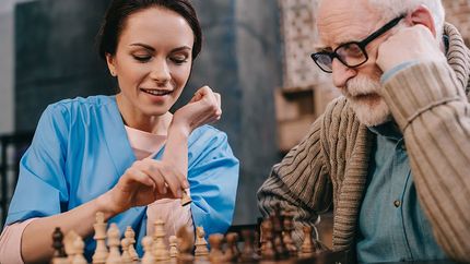 nurse playing chess with older man