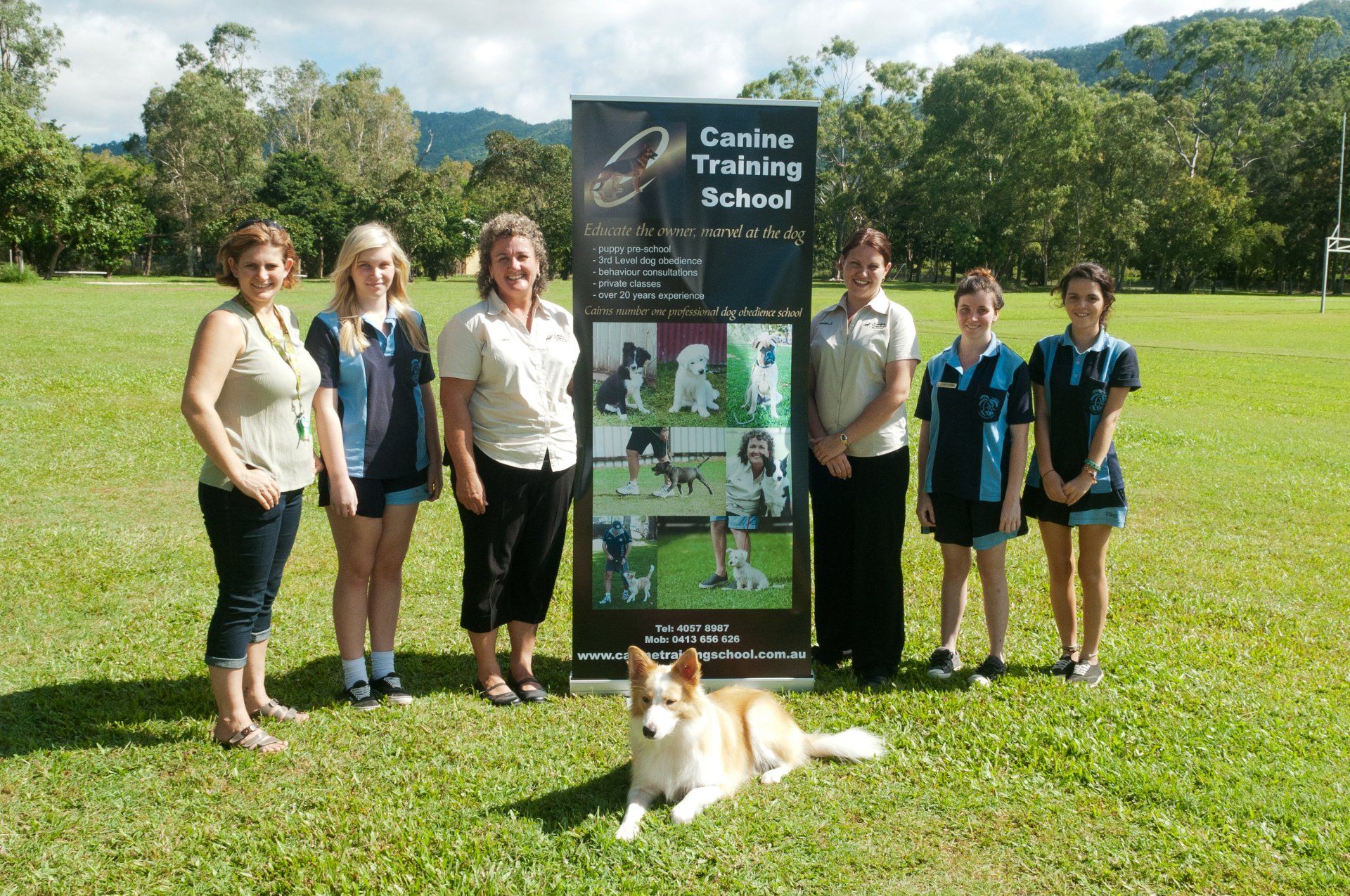 A Group Of People Standing In Front Of A Canine Training School Sign — Canine Training School In Cairns, QLD