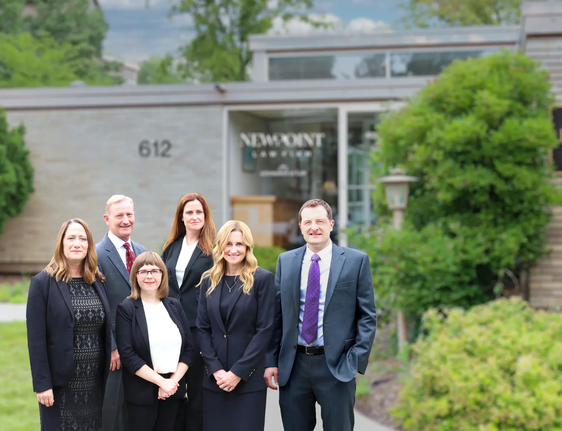 Group photo of the attorneys of New Point Law Firm standing in front of the law office building at 612 Kellogg Avenue in Ames, Iowa.