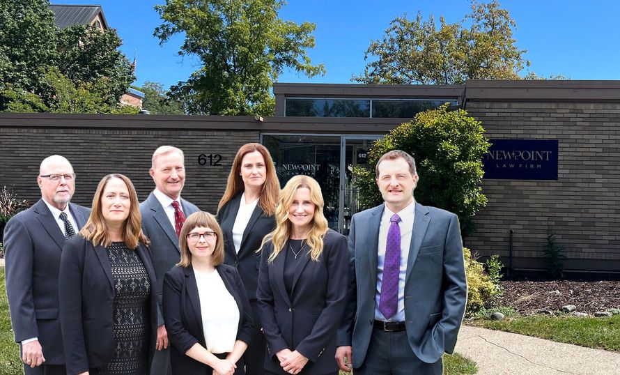 Group photo of the attorneys of New Point Law Firm standing in front of the law office building at 612 Kellogg Avenue in Ames, Iowa.