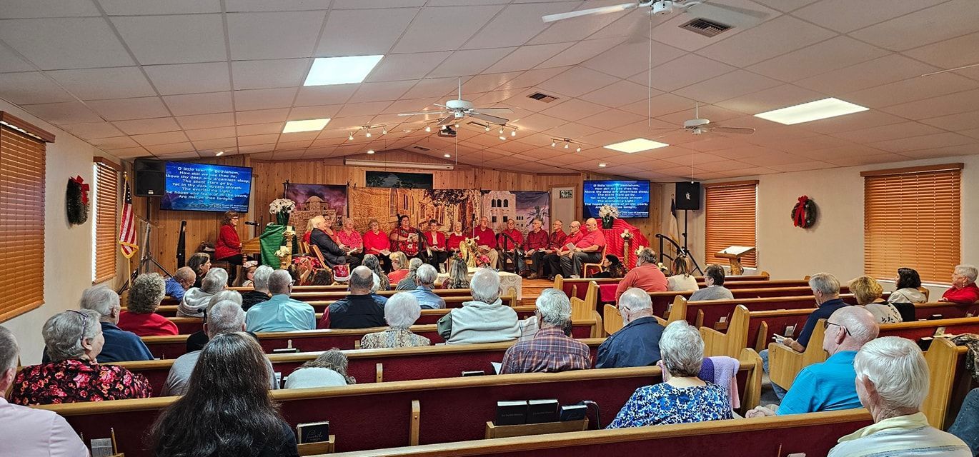 Hands clasped in prayer over an open Bible on a wooden surface, with a dark, blurred background.