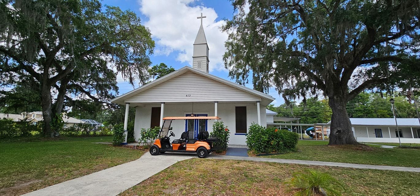 Audience watches a choir performing in a brightly lit church. Many seated, red choir robes, stage decorations.