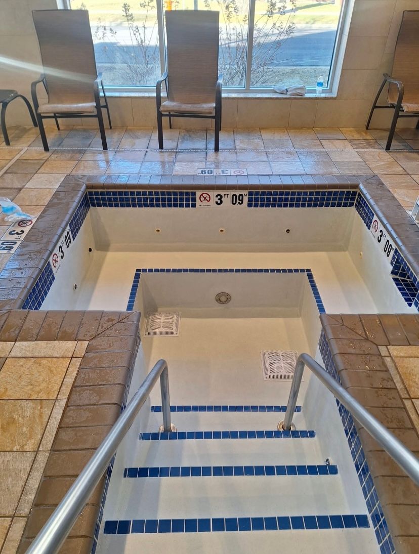 a hot tub with blue tiles and plastering after it went through  a full restoration project with Elite construction pools.