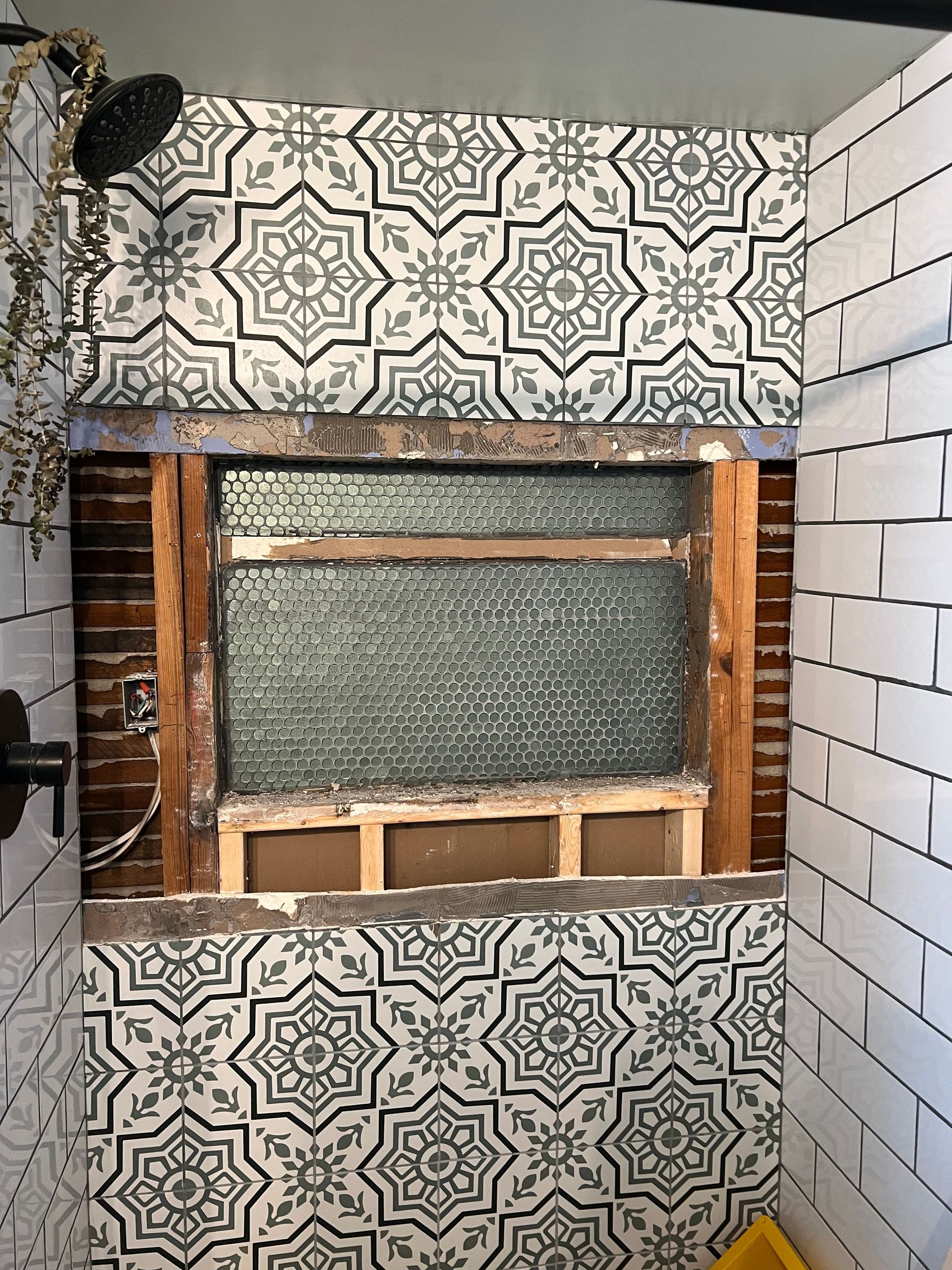 A bathroom with a tiled wall and a shower head.