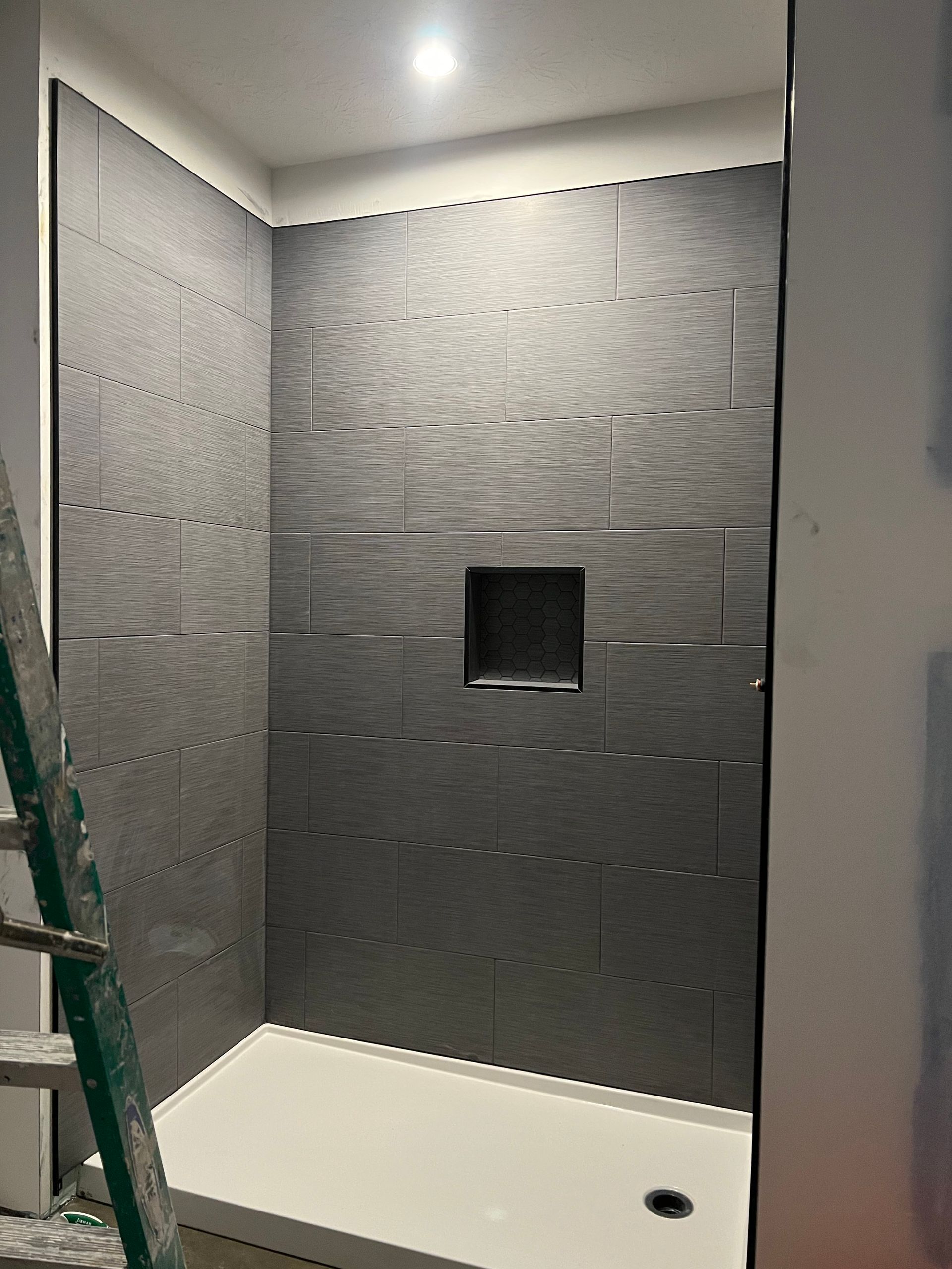 A bathroom with a walk in shower and a ladder.