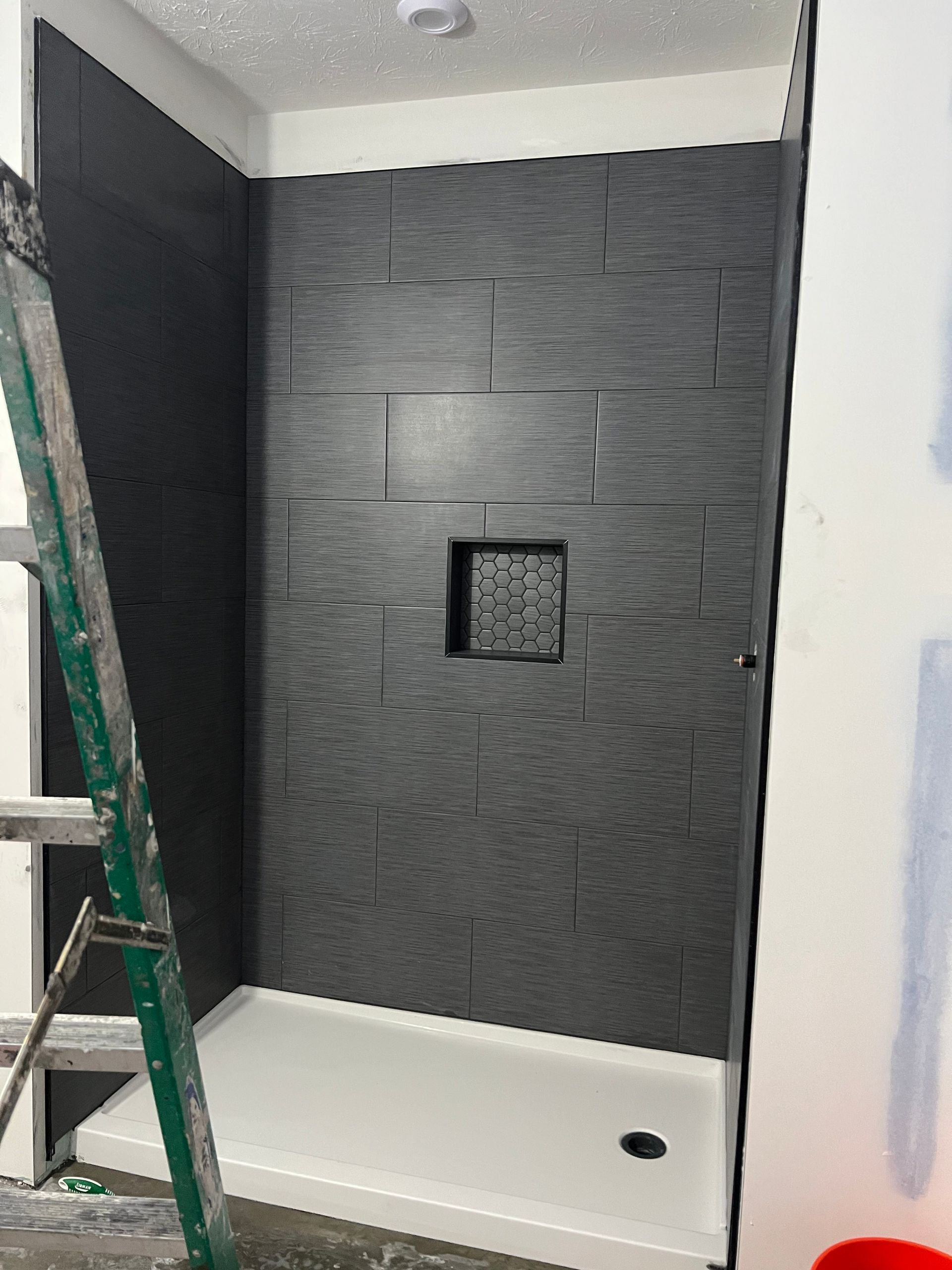 A bathroom with a shower stall and a ladder.