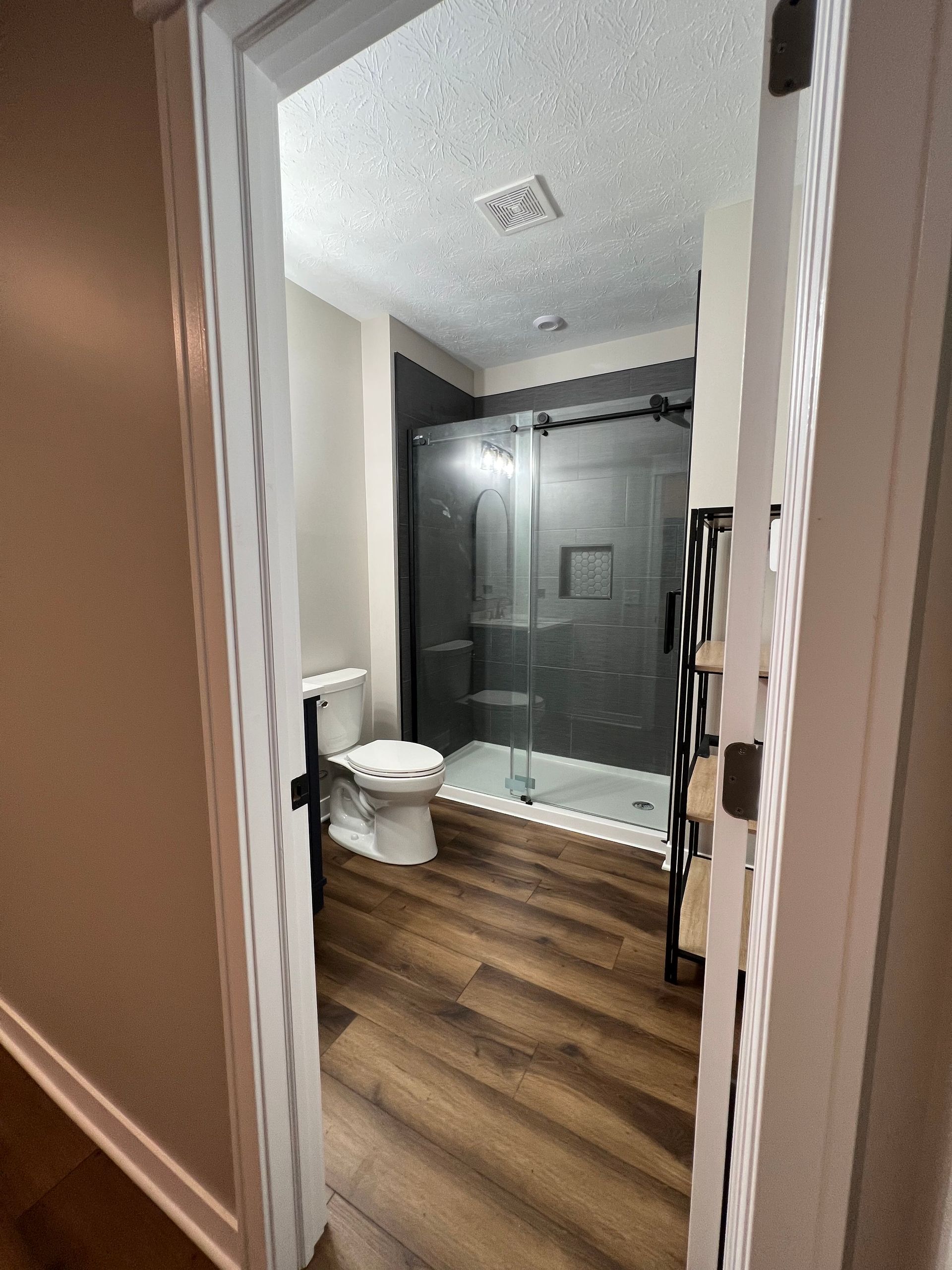 A bathroom with a toilet , shower and walk in shower.