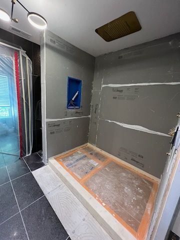 A bathroom with a walk in shower under construction.
