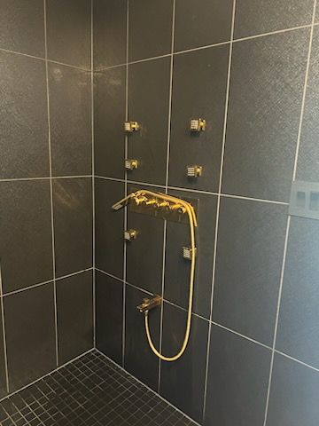 There is a shower with a yellow hose attached to the wall.